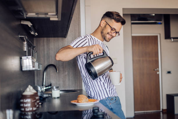 istock Happy young man enjoying his morning, preparing coffee and breakfast 1256109672