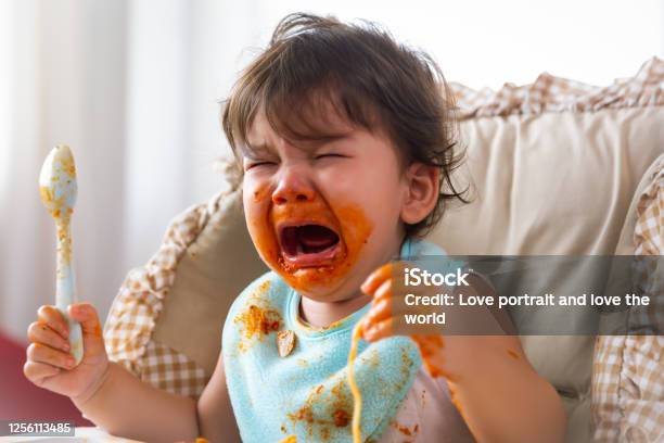 Adorable Little Toddler Girl Or Infant Baby Crying When Unsatisfied When Finished Eating Food On Baby Chair Cute Infant Girl Get Hungry And Want More Food Mix Race Daughter Get Dirty Kid Get Tantrum Stock Photo - Download Image Now