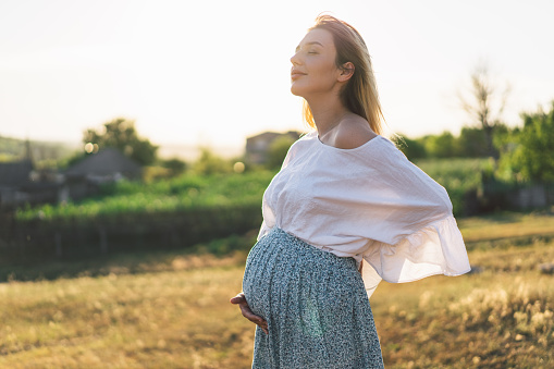 Happy Attractive pregnant woman in outdoors. Concepts of pregnancy and family
