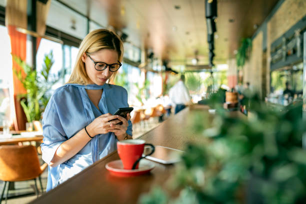 istock An Attractive Blonde Woman is Using her Mobile Phone for Online Browsing while Sitting in the Modern Cafe. 1256116056