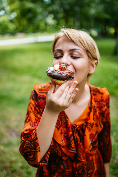 istock Woman eating donut in park 1256116415