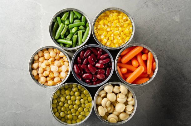 istock Flat lay view at canned vegetables in opened tin cans on kitchen table. Non-perishable long shelf life foods background 1256121099