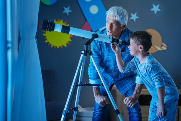 istock Child with grandfather using telescope during night 1256125344