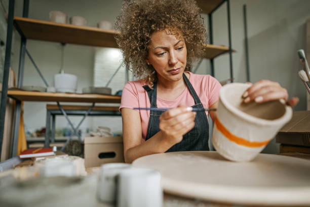 istock Artist painting concrete flower pot in her studio 1256127596