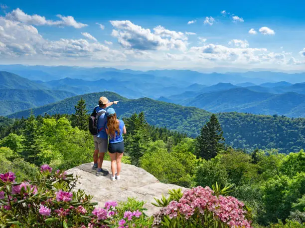 Photo of Couple on top of mountain looking at beautiful landscape.