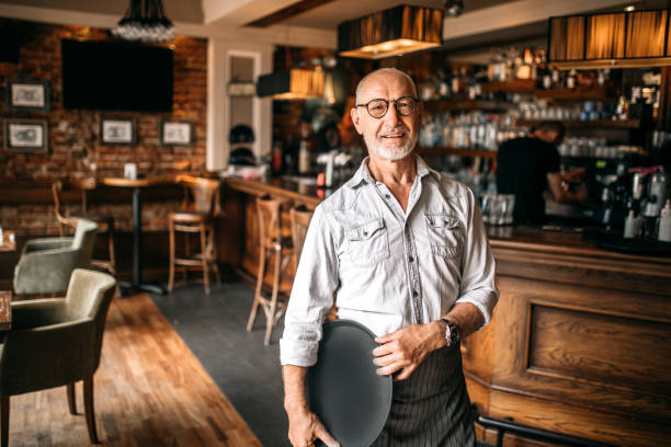 Senior Cafe Owner standing in his Restaurant after Reopening, proud on his business