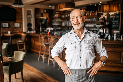 Senior Cafe Owner standing in his Restaurant after Reopening, proud on his business