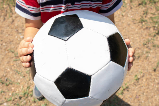 istock Kid holding the ball in two hands, flat lay. Sport concept 1256136897