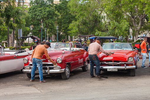 Havana, Cuba-October 07, 2016. Two drivers are cleaning and preparing for tourist their classic, old style, American cars after rain on October 07, 2016 at old part of Havana City in Cuba.