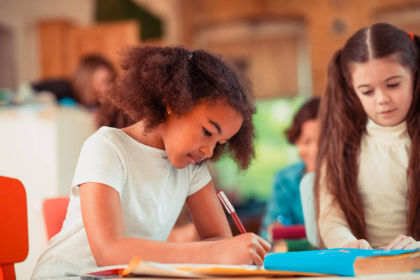 istock Attentive girl is concentrated on writing her assignment 1256139431