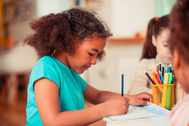 istock Girl drawing with a blue pencil during the art class 1256139465