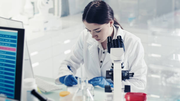 istock Female doctor making notes during research. Using microscope in genetic research lab 1256144308