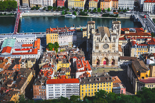 Aerial view of Lyon cityscape with St Jean Cathedral monument in foreground along Saone riverbank and red rooftops from large Place Bellecour famous town square. Photo taken in Lyon city, Unesco World Heritage Site, in Rhone department, Auvergne-Rhone-Alpes region in France, Europe during a sunny summer day.