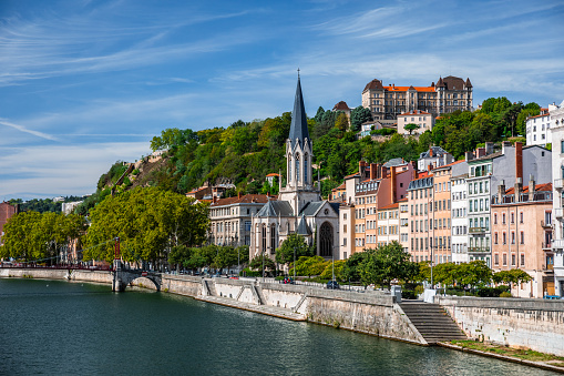 Saone riverbank in Lyon old town, Vieux Lyon district, with the Saint-Georges church majestic monument and colorful residential apartments. Photo taken in Lyon famous city, Unesco World Heritage Site, in Rhone department, Auvergne-Rhone-Alpes region in France, Europe during a sunny summer day.