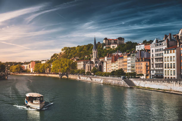 Saone riverbank in Lyon French city with Saint-Georges church and tourist tourboat along colorful apartments stock photo