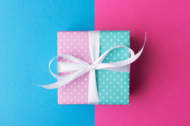 istock Pink and blue gift box with white bow over color paper background 1256154593