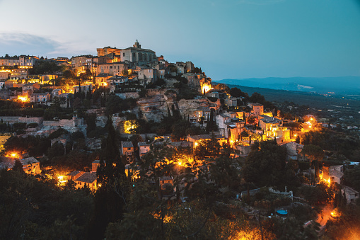 Panorama landscape cityscape of ancient medevial town Gordes illuminated with city lights at night in Provence, France. Luberon national park.