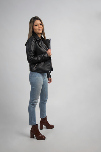 latin woman standing on boots wearing jeans and leather black jacket