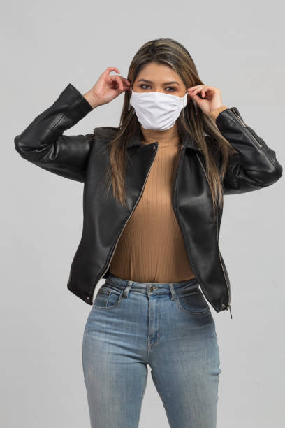 istock latin woman puttin on her face mask 1256157596