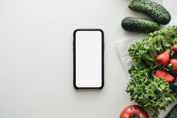 istock Smartphone with white screen and vegetables on a table, mock up. 1256157791