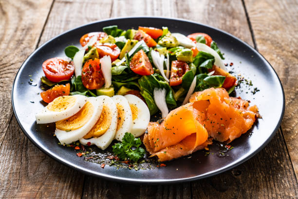 istock Smoked salmon with hard-boiled eggs, avocado and vegetables on wooden table 1256162385