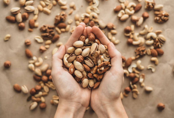 istock Different types of nuts, nut mix of almonds, hazelnuts, cashews, peanuts in hand 1256166079