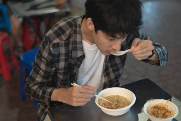 길거리 음식에서 수프 국수를 먹는 청년 - thai cuisine thailand asian cuisine chinese cuisine 뉴스 사진 이미지