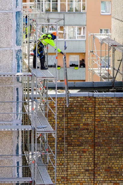 istock the worker assembles the scaffolding on the facade of a multi-storey house at a dangerous height 1256168043