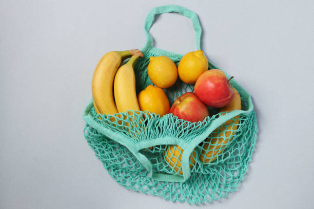 istock Yellow ripe bananas, lemons and apples in reusable string mesh bag turquoise color on light background, Zero waste concept, Flat lay 1256168507