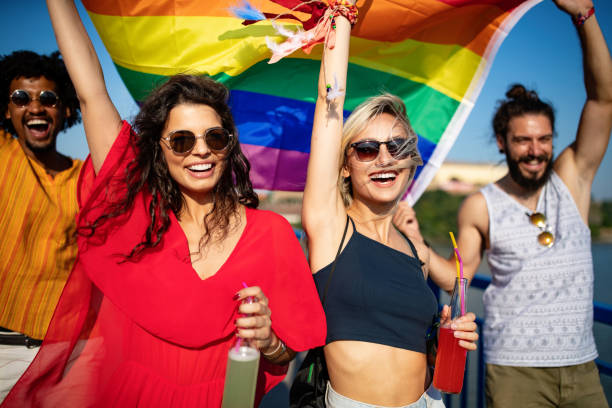 glückliche gruppe von menschen hängen in der stadt winken lgbt mit stolz flagge - pride lgbtqi veranstaltung stock-fotos und bilder