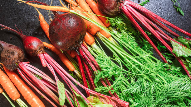 istock carrots with green stems and beets with leaves on a black table. copy space, close up, 1256180209