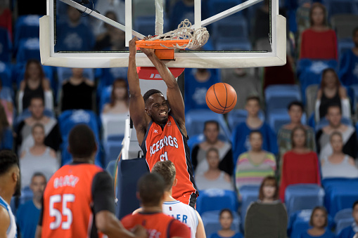 Basketball player in red jersey dribbling ball during match.