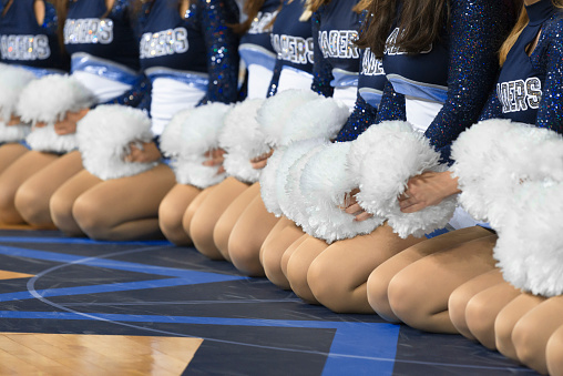 Mid section of cheerleaders kneeling on basketball court.