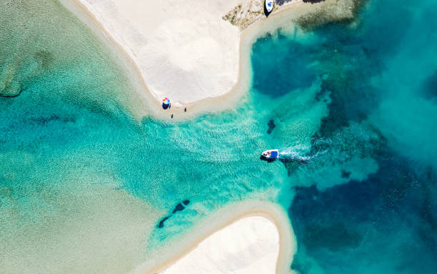 foto aerea di spiaggia bianca e laguna di mare blu con barca a motore. cetifie, grecia. sfondo estivo. - vacations halkidiki beach sand foto e immagini stock