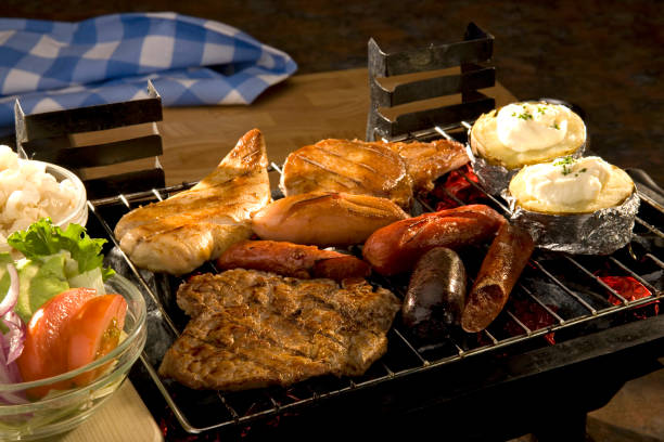 Assorted meats on a barbecue grill Assortment of meats on a grill at a barbecue cooked and ready to eat. Salad on the side. Food still life. baked potato sour cream stock pictures, royalty-free photos & images