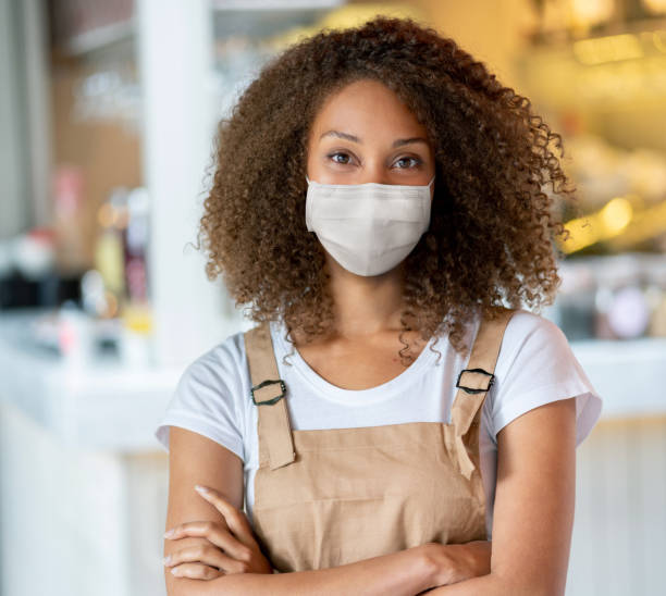 istock Happy waitress working at a cafewearing a facemask 1256186620
