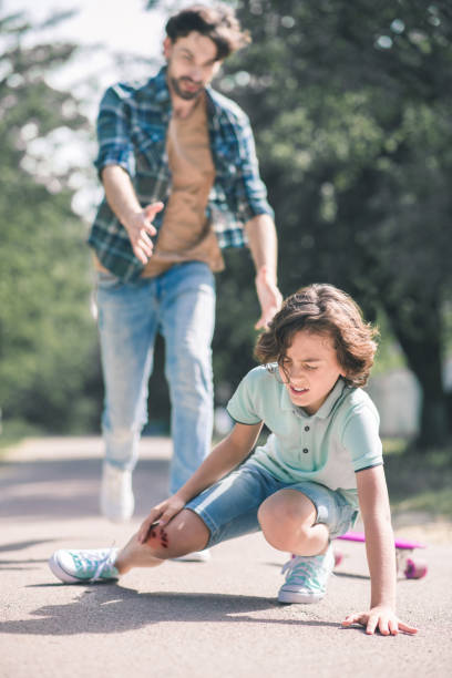 istock Dark-haired boy falling down on the ground, his father rushing to help him 1256186783