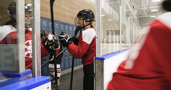 A woman’s hockey team entering the ice rink in an arena.