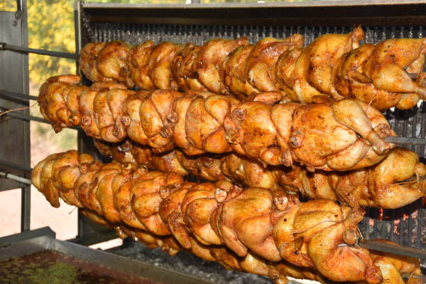 roasted chickens on spit grilled over fire of a big barbecue in germany - chicken rotisserie roast chicken barbecue grill imagens e fotografias de stock