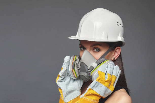 istock Construction girl in a white hard hat and protective construction mask, for heavy work where you need protection from inhaling harmful gases and sprayed particles in the air. 1256208691