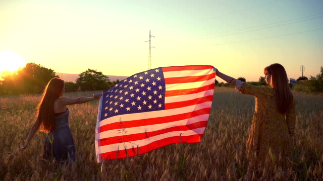 Two girls in a wheat field with American flag