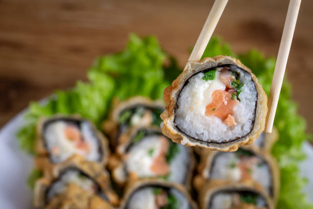 sushi frito quente com salmão, cebolinha e queijo. cardápio de sushi. comida japonesa. com fundo desfocado - sushi chopsticks sushi bar food - fotografias e filmes do acervo