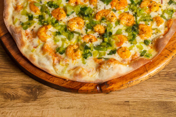 shrimp pizza with leeks on wooden background.