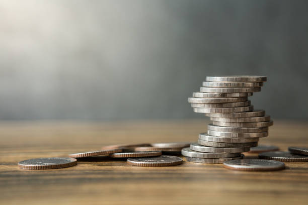 istock Stack of coins on wood desks and loft wall backgrounds with sunlight 1256220432