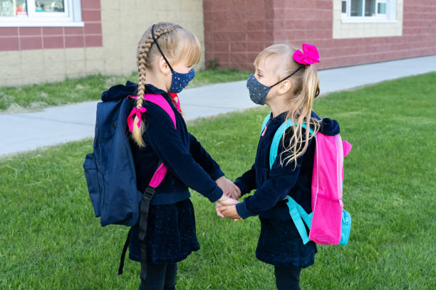 safety back to school concept, wearing mask for students. two young sisters going to school. friendship, family - backpack student report card education imagens e fotografias de stock