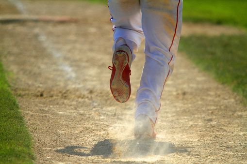 A baseball player breaks out of the batters box after hitting the ball.