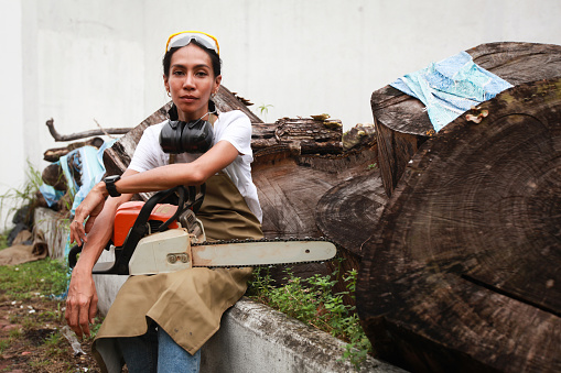 Portrait of A Woman Carpenter Holding A Chainsaw