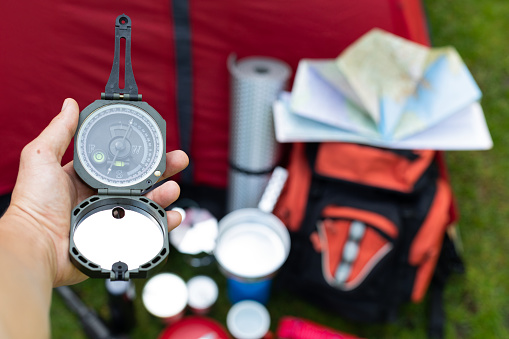 Picture of camping tools on the grass - backpack, tent, gas tank, cans, compass, etc - ready to go in the woods