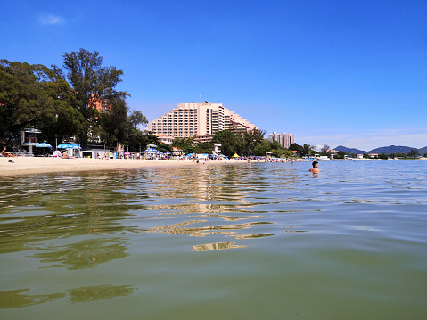 People sunbathing and swimming at Hong Kong Gold Coast golden beach, Tuen Mun, New Territories, Hong Kong.