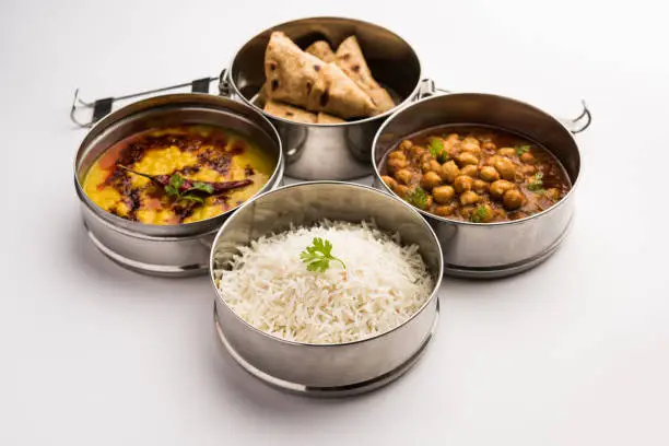 Indian vegetarian Lunch Box or Tiffin made up of stainless steel for office or workplace, includes Dal Fry, Chole Masala, Rice with chapati and salad